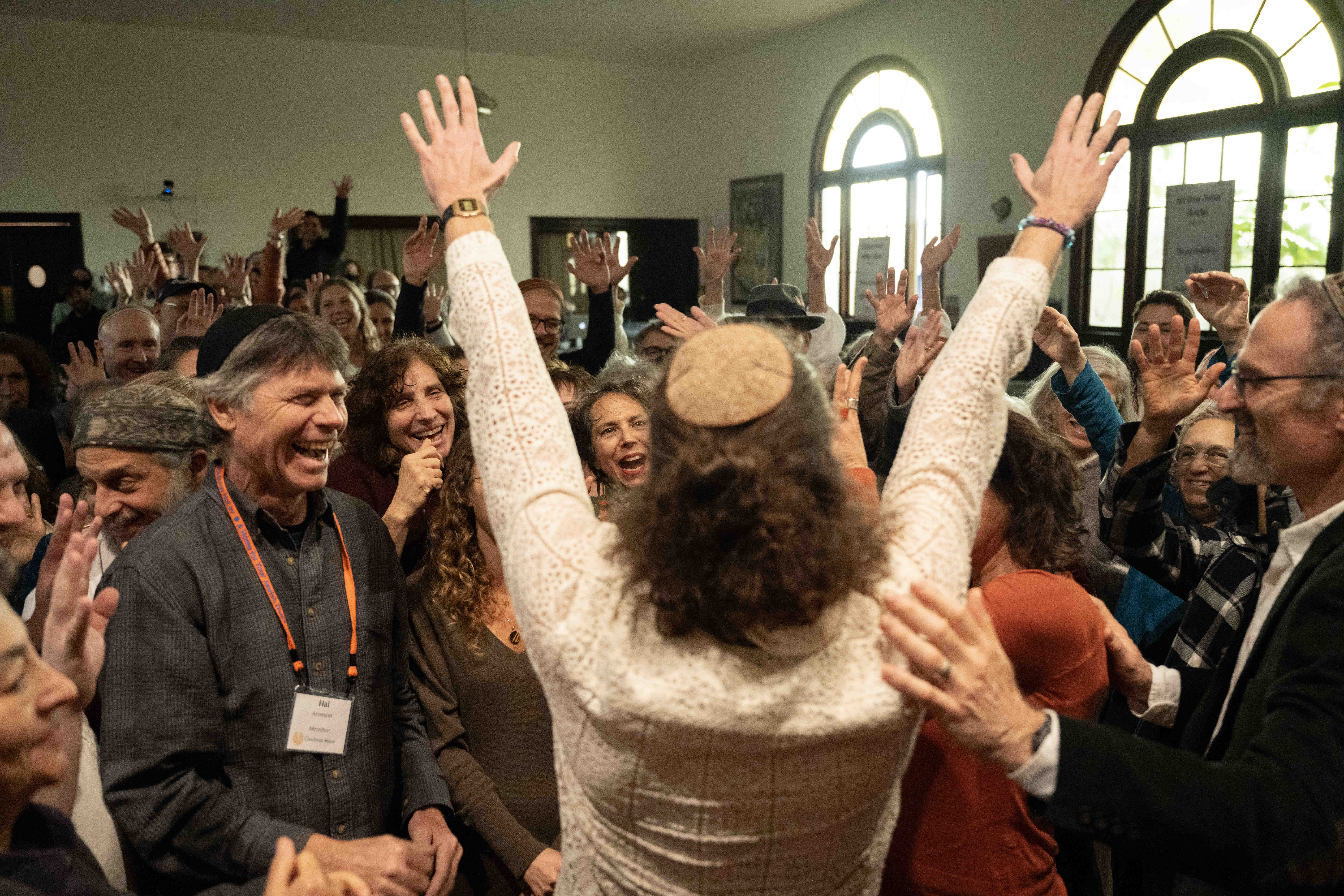 Rabbi Zvika Krieger holds his hands up above the congregation after congregants bless him during a celebration for Zvika Krieger’s rabbinic ordination and installation at the Renewal synagogue Chomat HaLev in Berkeley on Saturday, Jan. 25, 2025. (Aaron Levy-Wolins/J. Staff)